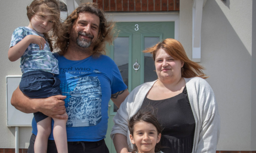 family smiling with kids infront of their home